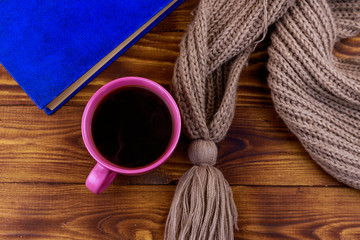 Fototapeta na wymiar Cup of coffee, knitted scarf and book on wooden background