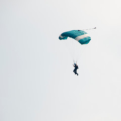 Parachutist on blue sky preparing for landing