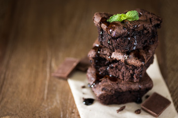 A stack of chocolate brownies on wooden background with mint leaf on top, homemade bakery and dessert
