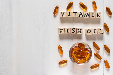 Vitamin D from Fish oil capsules in an orange bottle on white wooden background, supplemental and healthcare product, flat lay surface