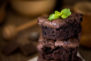 A stack of chocolate brownies on wooden background with mint leaf on top, homemade bakery and dessert