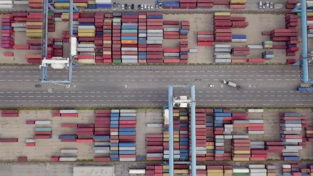 Transtainer yard - Various brands and colours of Shipping containers stacked by Transtainers (Mobile gantry cranes) off of service trucks - Top down aerial footage.