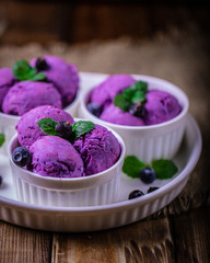 Scoops of blueberry ice cream on a white ceramic plate