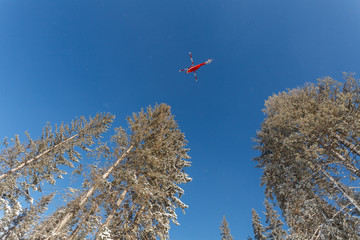Czerwony helikopter na tle niebieskiego zimowego nieba - obrazy, fototapety, plakaty
