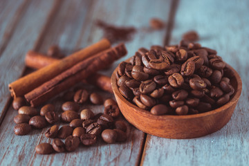 Coffee beans and cinnamon on wooden texture and background, using color grading effect
