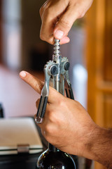 Hand waiter opening crok wine with lever opener