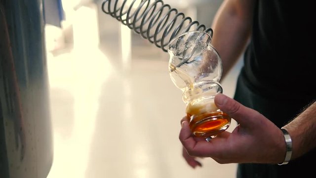 Brewer takes a sample of beer from the tank