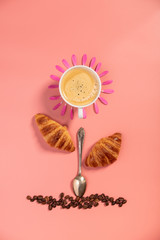 Creative layout made of coffee cup, croissants, coffee beans and flowers on pink background