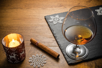Glass of cognac and cigar with snack on the wood table with stone cutting board. Top view with copy space