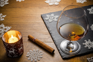 Glass of cognac and cigar with snack on the wood table with stone cutting board. Top view with copy...