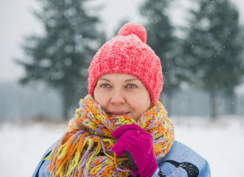 An adult woman in winter clothes enjoys the beauty of the winter forest.