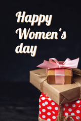 Holiday boxes Packed in crafting paper on dark wooden background. Vertical card Happy Women's day with text