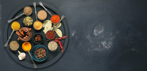 Colorful, aromatic spices in bowls on a dark background. Top view.