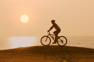 Fototapeta na wymiar silhouette of cyclist on sunset or sunrise sky background