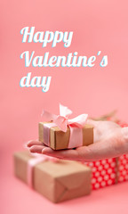 Hands holding gift box Packed in Kraft paper on pink background. Holiday vertical card Happy Valentine's day with text