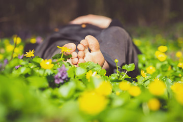 Man lies barefoot among fresh yellow wildflowers