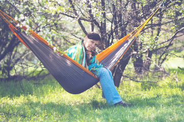 Happy woman with her funny dog, dachshund is relaxing in a hammock