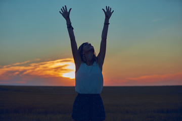 Cute young woman jumping in a wheat field.