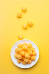 Cheese ball in a ceramic dish on yellow background. Top view.