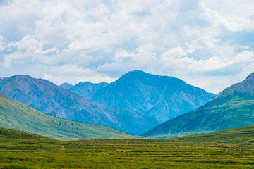 Spectacular view of giant mountains under cloudy sky. Huge mountain range at overcast weather. Wonderful wild scenery. Atmospheric dramatic highland landscape of majestic nature. Scenic mountainscape.