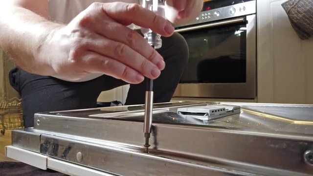 Male Technician repairing dishwasher In Kitchen