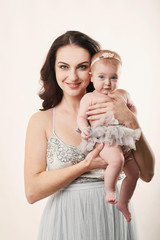young attractive mother with a little girl on a light background