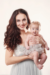 young attractive mother with a little girl on a light background