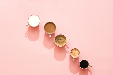 Many cups of coffee and shadows on a gently pink background. Top view