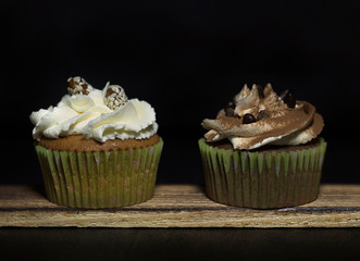 lighted cupcakes on a wooden board against a black background