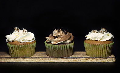 lighted cupcakes on a wooden board against a black background