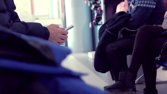 People are waiting for their flight with mobile phone, hands close-up.