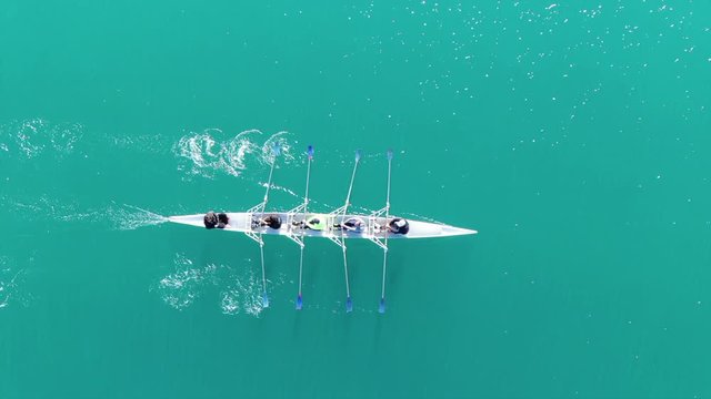 Aerial drone bird's eye view video of sport canoe operated by team of young women in turquoise clear waters