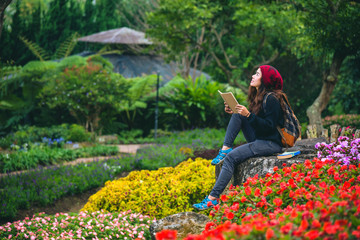 woman travel nature in the flower garden. relax sitting on rocks and reading books In the midst of nature at national park doi Inthanon...