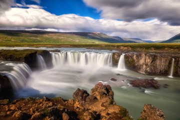 Godafoss (Akureyri) waterfall at sunny day, spectacular landscape of Iceland iconic place with blue cloudy sky, long exposure. Skjalfandafljot river, Norðurland, North of Iceland