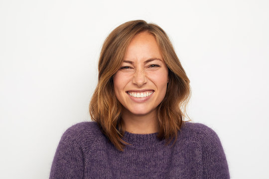 portrait of a young happy woman smiling giggles on white background looking in camera