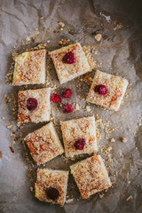 Sliced homemade cake with frozen raspberries on top on the dark background