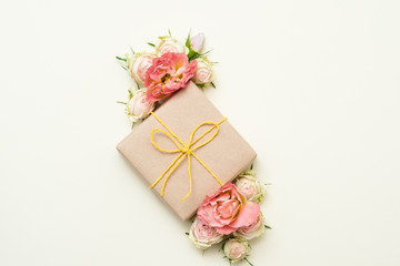 Anniversary present. Craft paper gift box on ivory background. Minimal floral decor. Flat lay.