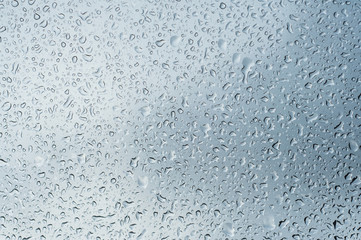 closeup of rain drops on window on cloudy sky background