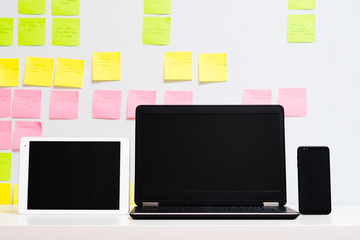 Gadgets technology in working and planning. Laptop tablet and mobile phone on defocused sticker wall background.