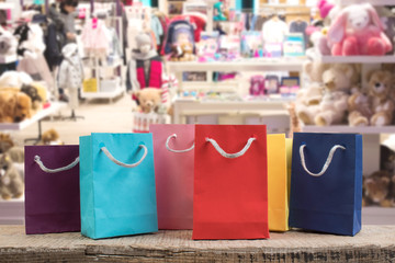 A lot of multi-colored paper shopping bags on a wooden table in a shop. Front view.