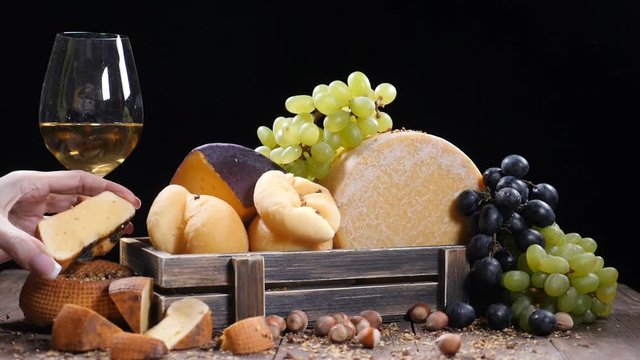 Restaurant craft cheese . Variety of hard cheese put in a beautifully composition. Wine is pouring into a flass in slow motion. Wine and appetizer concept. Luxury restaurant concept. female hand