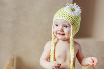 Close up portrait of cute adorable baby girl in knitted hat lying on bed