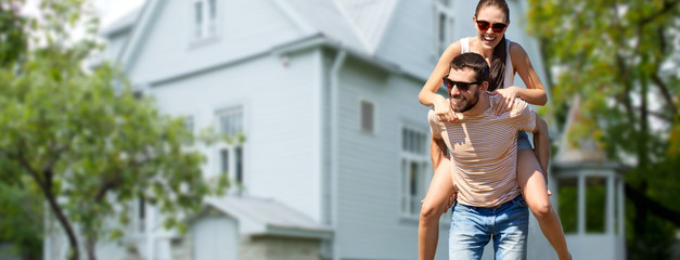 real estate and people concept - happy couple having fun in summer over house background