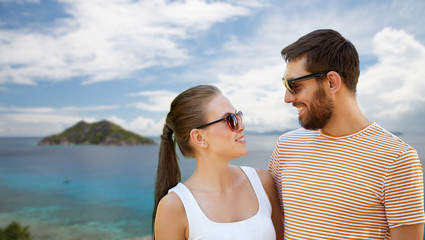 Fototapeta premium travel, tourism and people concept - happy couple in sunglasses outdoors over tropical beach on seychelles island background