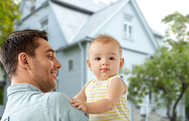 family, fatherhood and people concept - father with little baby daughter over living house background