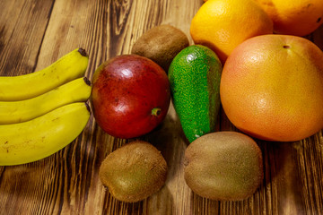 Assortment of tropical fruits on wooden table. Still life with bananas, mango, oranges, avocado, grapefruit and kiwi fruits
