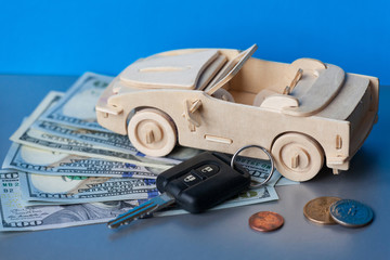 Wooden Toy Car and key vehicle with money on green background.