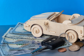 Wooden Toy Car and key vehicle with money on green background.