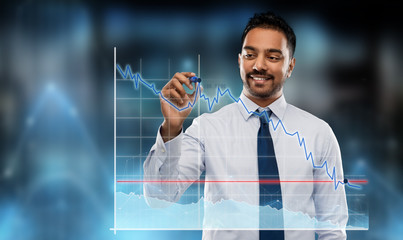 business, statistics and people concept - smiling indian businessman with marker drawing chart on...