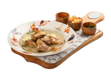Quail broth with crackers and herbs on a wooden board. On white background.